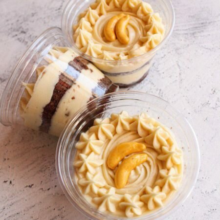 На фотографии десерт Банановый в стаканчике, шоколадный бисквит с заварным кремом, производитель кондитерских изделий под заказ Шарлотка.