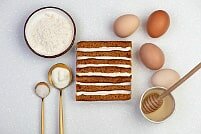 На фото яйца, крем, медовые коржи, ингредиенты для торта, производитель кондитерских изделий под заказ Шарлотка.