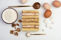 На фото орехи, яйца, крем, коржи, ингредиенты для торта, производителя кондитерских изделий под заказ Шарлотка.