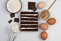 На фотографии шоколад, яйца, крем, коржи, ингредиенты для шоколадно-бананового торта, производителя кондитерских изделий под заказ Шарлотка.
