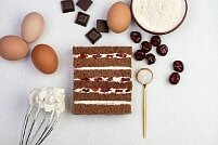 На фото кусочки шоколада, яйца, крем, бисквит, ингредиенты для торта, производитель кондитерских изделий под заказ Шарлотка.