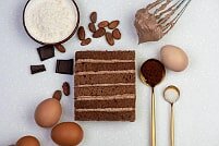 На фото шоколад, яйца, крем, коржи, ингредиенты для шоколадного торта, производителя кондитерских изделий под заказ Шарлотка.