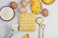 На фото кусочки ананаса, яйца, крем, бисквит, ингредиенты для торта, производителя кондитерских изделий под заказ Шарлотка.